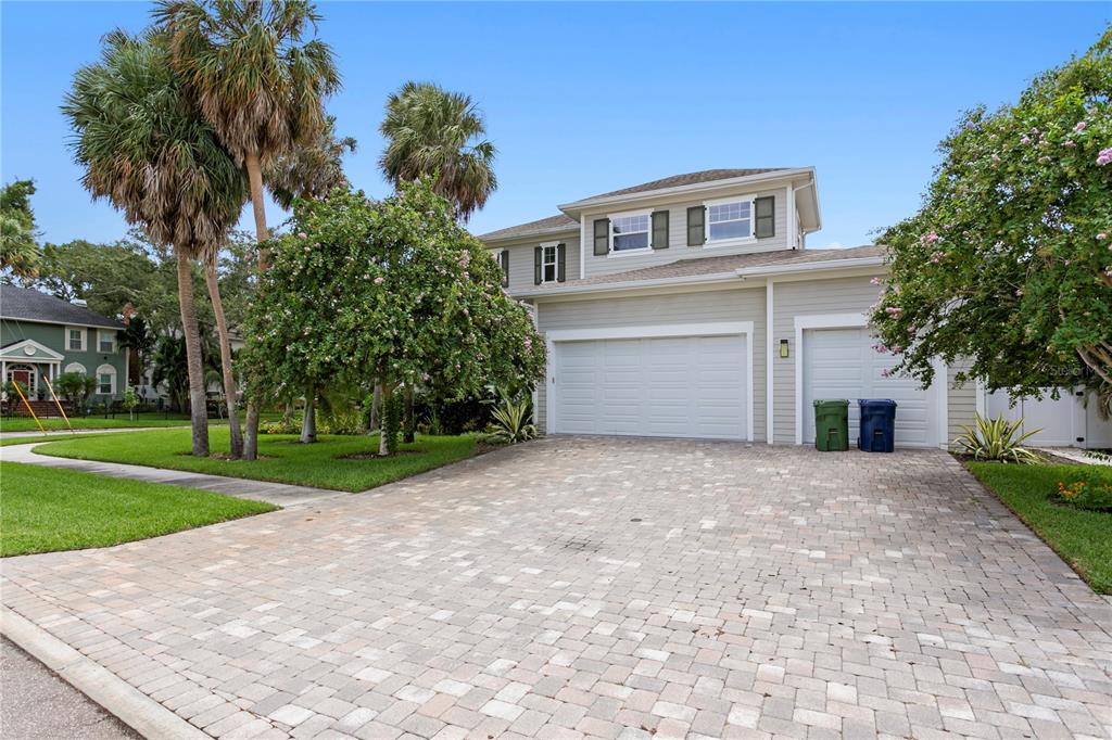 A two-story house with light gray siding, a paver driveway, and an attached three-car garage — 5016 W EVELYN DRIVE, TAMPA, FL