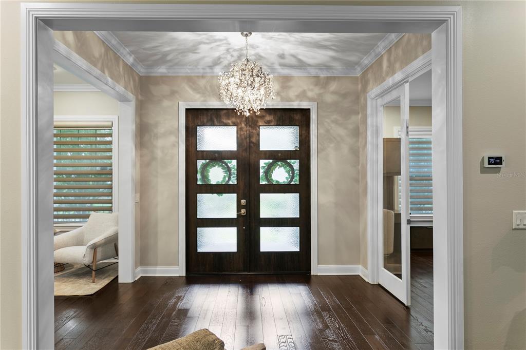 A foyer features dark hardwood floors, a crystal chandelier, and double front doors with glass — 5016 W EVELYN DRIVE, TAMPA, FL