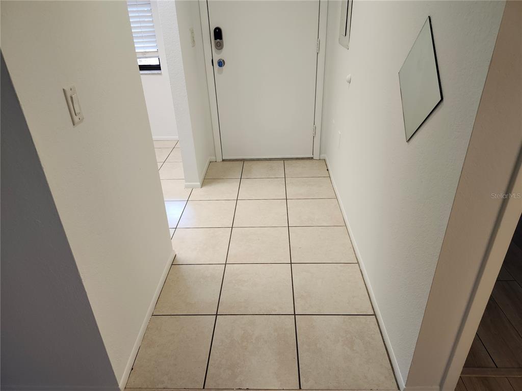 An entryway features beige tiled flooring, white walls, and a white front door — 2808 60TH AVENUE W UNIT 302, BRADENTON, FL