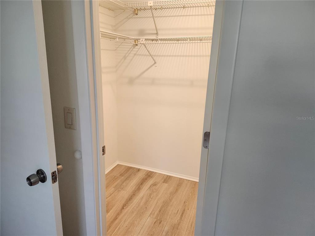 A walk-in closet features white wire shelving and light wood-look flooring — 2808 60TH AVENUE W UNIT 302, BRADENTON, FL
