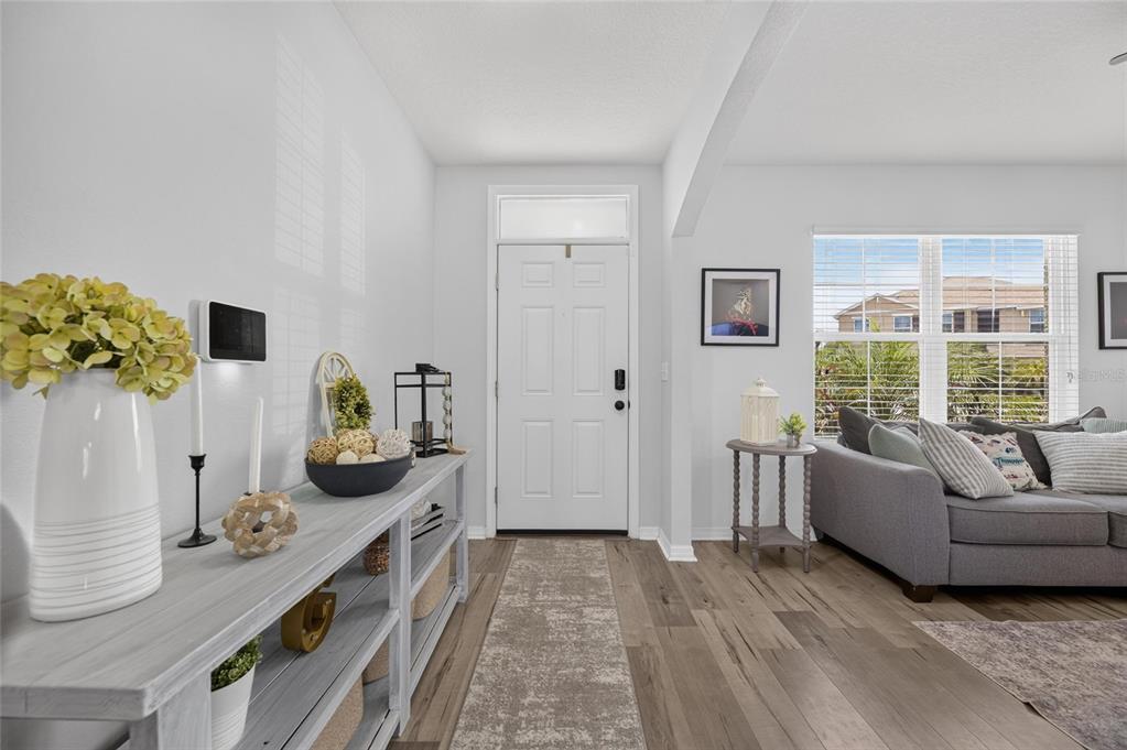 An entryway features a white door, light wood flooring, and a console table with decor — 8115 HARWICH PORT LANE, GIBSONTON, FL