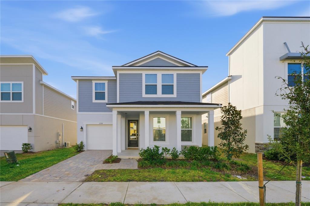 A two-story house with light blue siding, a front porch, and a single-car garage — 2308 DISTANT SUN TRAIL, KISSIMMEE, FL