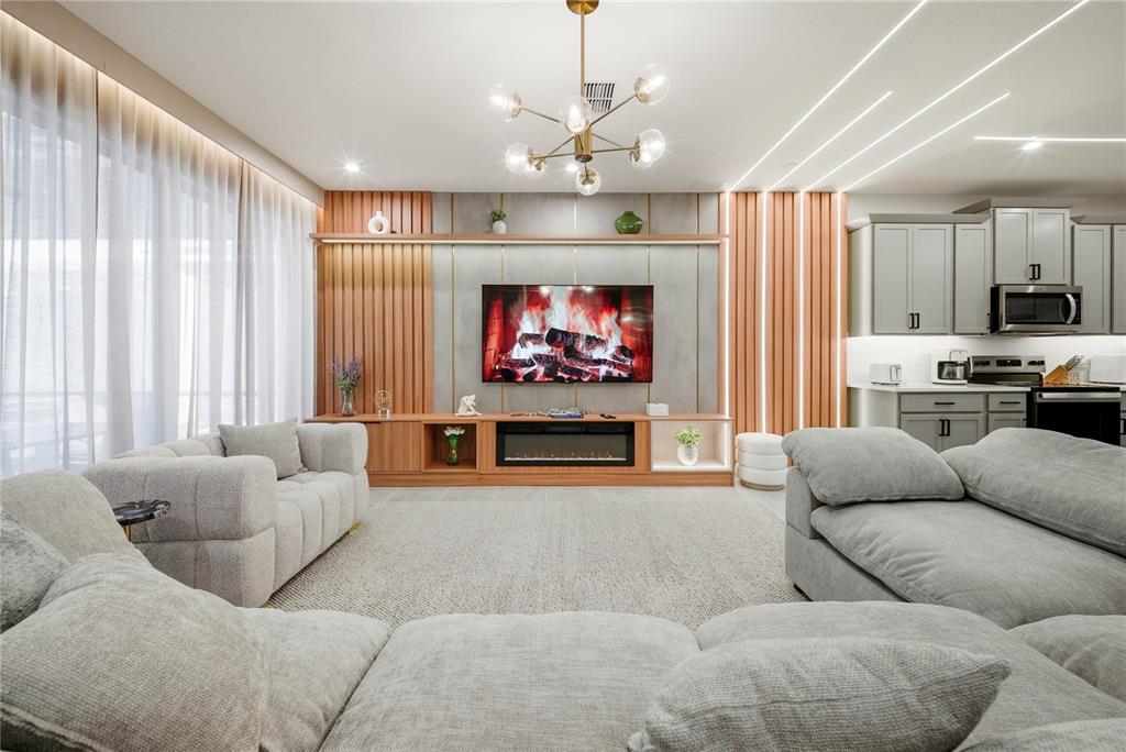 A living room features a modern fireplace, wood-slat wall accents, and gray sectional sofas — 2308 DISTANT SUN TRAIL, KISSIMMEE, FL
