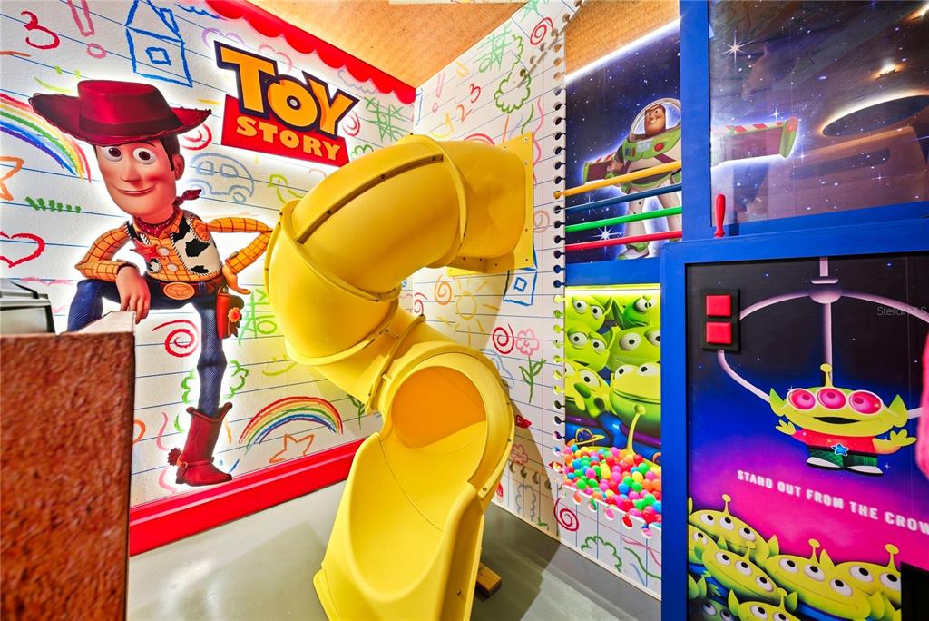 A Toy Story themed playroom features a yellow spiral slide and wall murals of characters — 2308 DISTANT SUN TRAIL, KISSIMMEE, FL