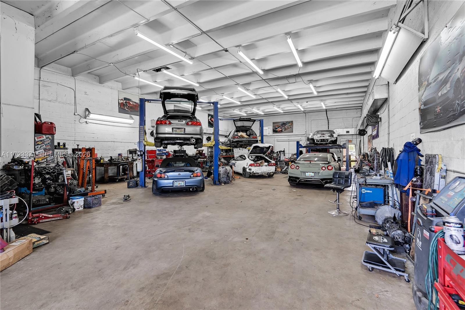 An automotive repair shop features multiple car lifts, several vehicles, and exposed ceiling lighting — 2700 W 79th St, Hialeah FL 33016, HIALEAH, FL