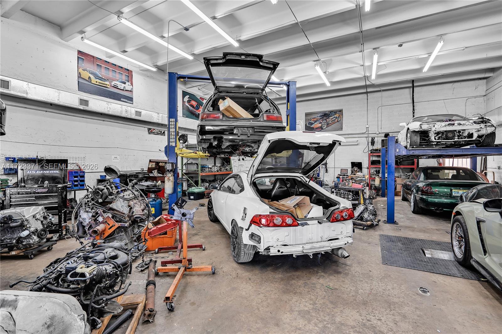 An automotive repair shop features multiple cars on lifts and various engines on the floor — 2700 W 79th St, Hialeah FL 33016, HIALEAH, FL