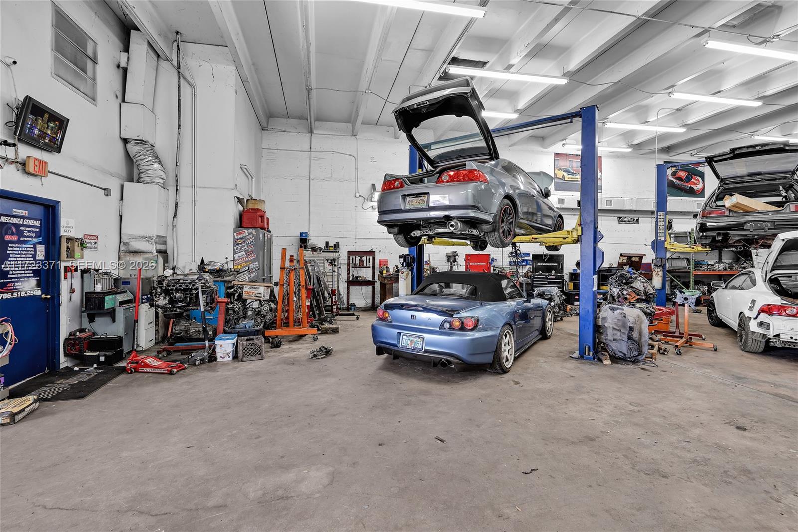 An auto repair shop interior features a car on a lift and several parked vehicles — 2700 W 79th St, Hialeah FL 33016, HIALEAH, FL