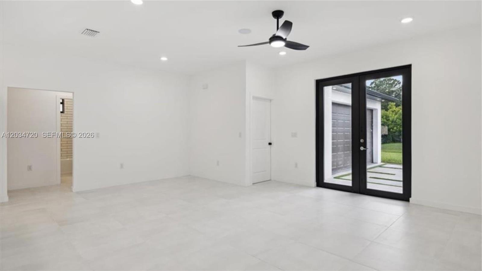 An empty room with white walls, light tile floors, a ceiling fan, and glass doors — 1310 Jefferson Ave, Lehigh Acres FL 33972, LEHIGH ACRES, FL
