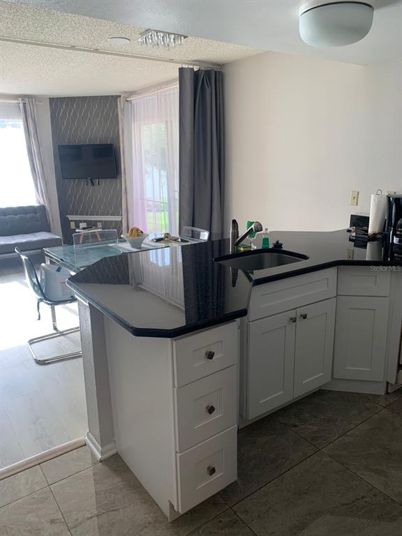 A kitchen island with a black countertop and white cabinets sits in a living area — 6337 PARC CORNICHE DRIVE UNIT 2107, ORLANDO, FL