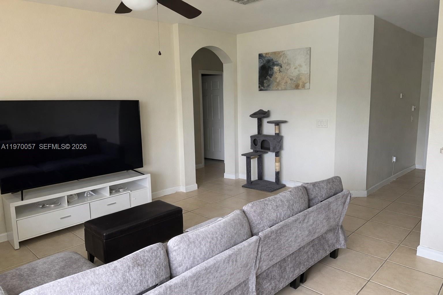 A living room features a large television, a grey sofa, and a cat tree — 1485 NE 33rd Rd # 207, Homestead FL 33033, HOMESTEAD, FL