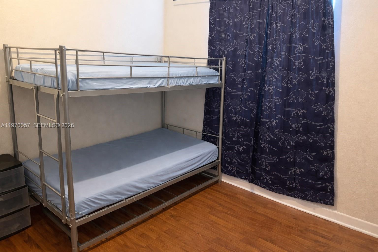 A bedroom features a silver metal bunk bed with blue bedding and dinosaur-patterned curtains — 1485 NE 33rd Rd # 207, Homestead FL 33033, HOMESTEAD, FL