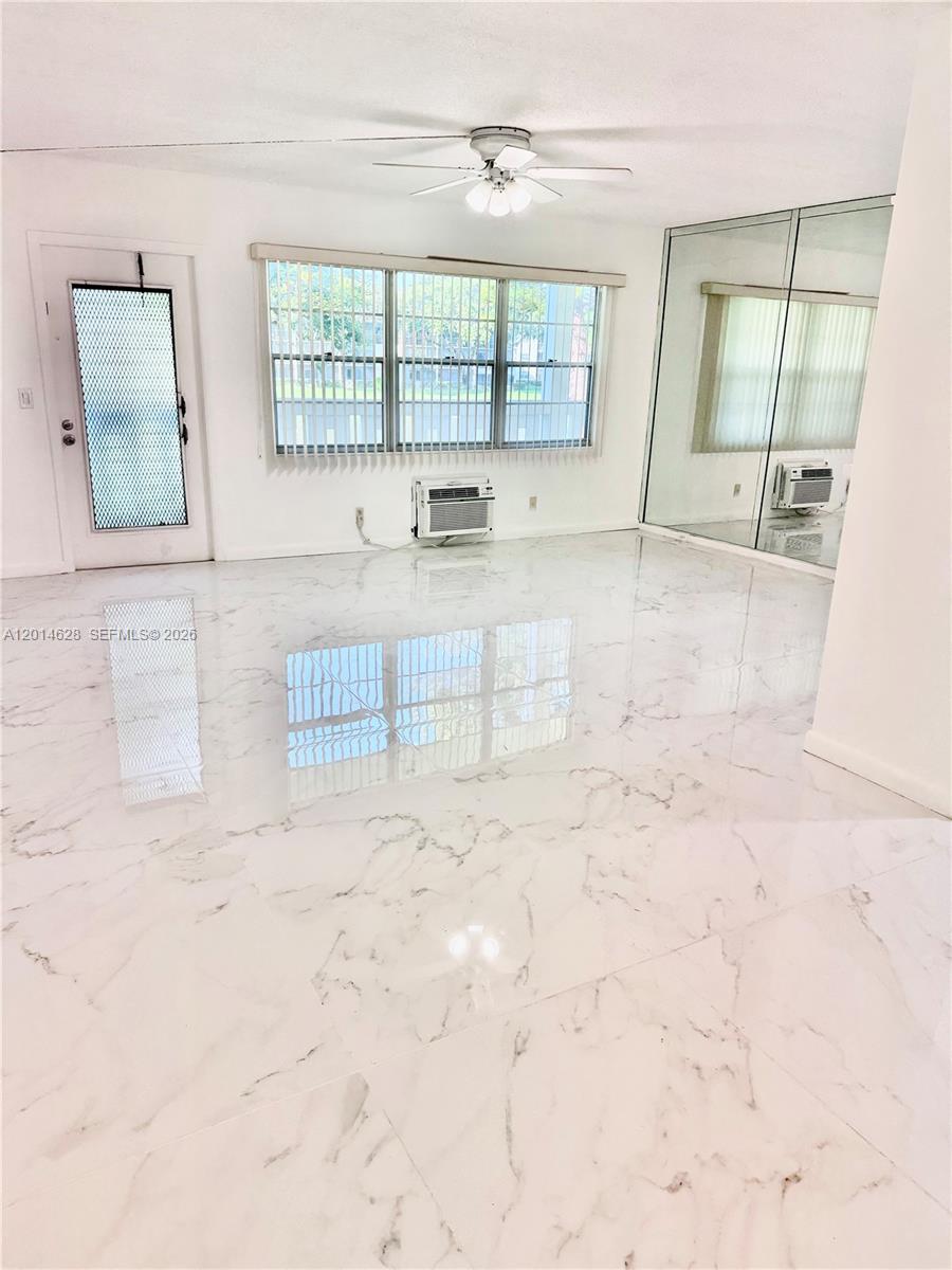 A bright room features white marble-look tile flooring, a ceiling fan, and a mirrored wall — 272 Dorset # G, Boca Raton FL 33434, BOCA RATON, FL