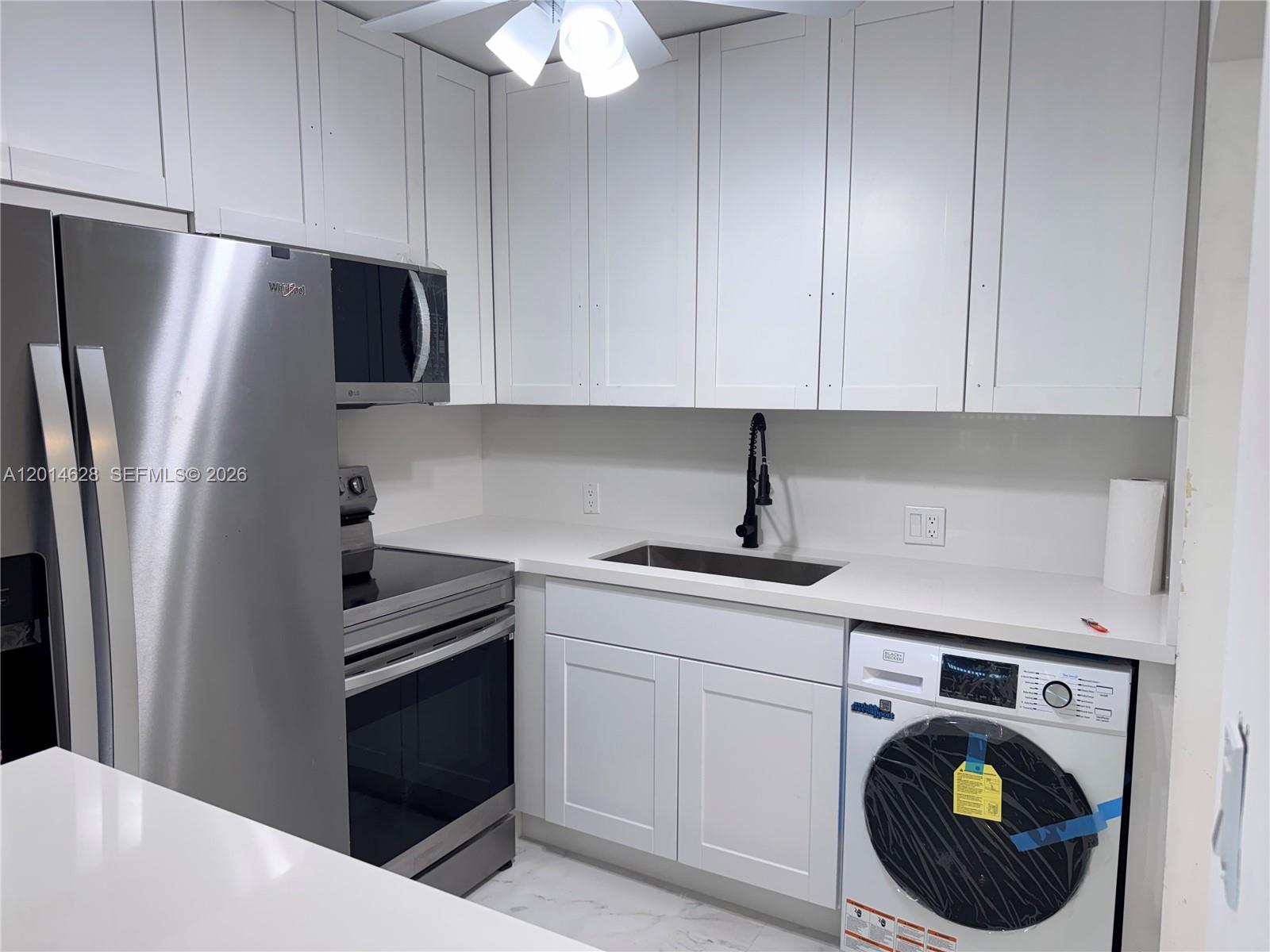 A kitchen features white cabinets, stainless steel appliances, a sink, and a built-in washing machine — 272 Dorset # G, Boca Raton FL 33434, BOCA RATON, FL