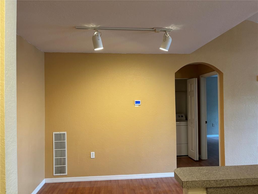 A room with yellow walls, wood flooring, a track lighting fixture, and an arched doorway — 7411 VISTA WAY UNIT 203, LAKEWOOD RANCH, FL