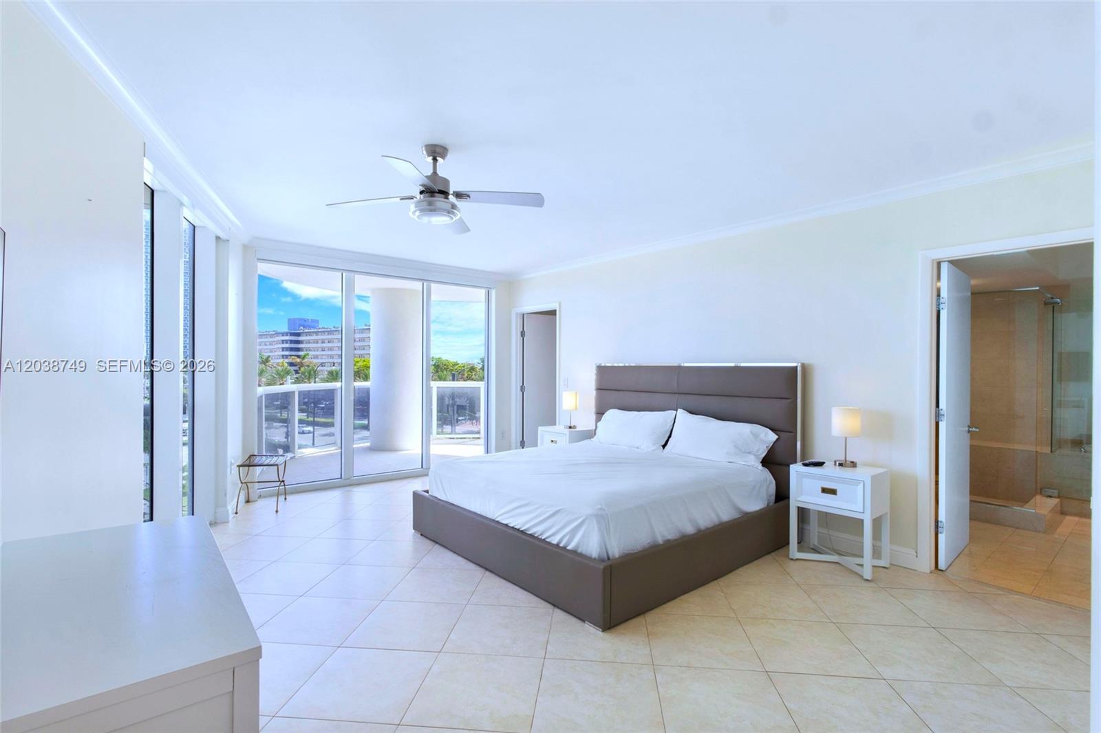 A spacious bedroom features a platform bed, tile flooring, and a large balcony with views — HALLANDALE BEACH, FL