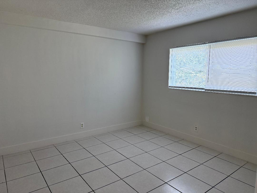 An empty room with white walls, a window with blinds, and light-colored tiled flooring — 1913 NE 2nd Street # 4, Pompano Beach FL 33060, POMPANO BEACH, FL