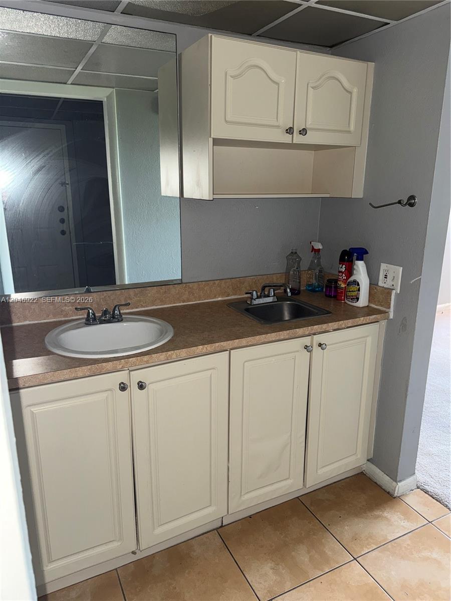 A bathroom vanity features a double sink, beige laminate countertop, and off-white cabinets — 6960 Miami Gardens Dr # 431A, Hialeah FL 33015, HIALEAH, FL