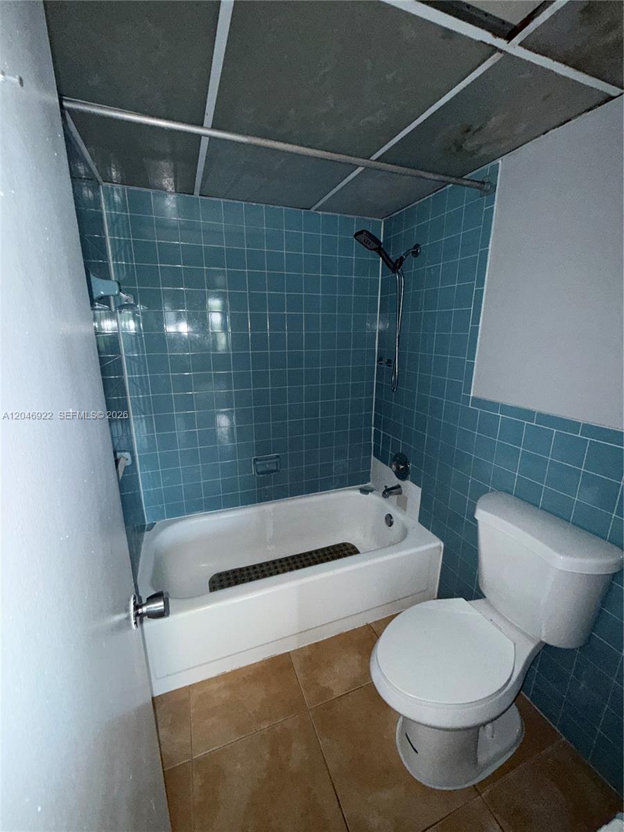 A bathroom features a white bathtub with blue tiled walls and a white toilet — 6960 Miami Gardens Dr # 431A, Hialeah FL 33015, HIALEAH, FL