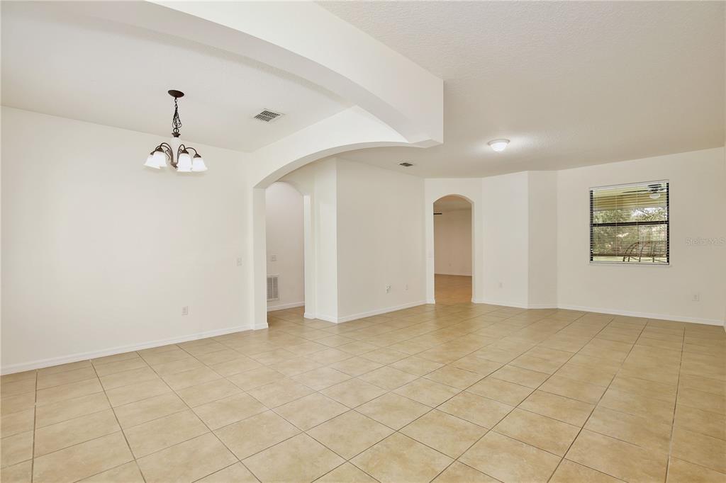 An open-concept dining area features beige tile flooring, white walls, and an arched architectural detail — 3908 COASTAL BREEZE DRIVE, KISSIMMEE, FL