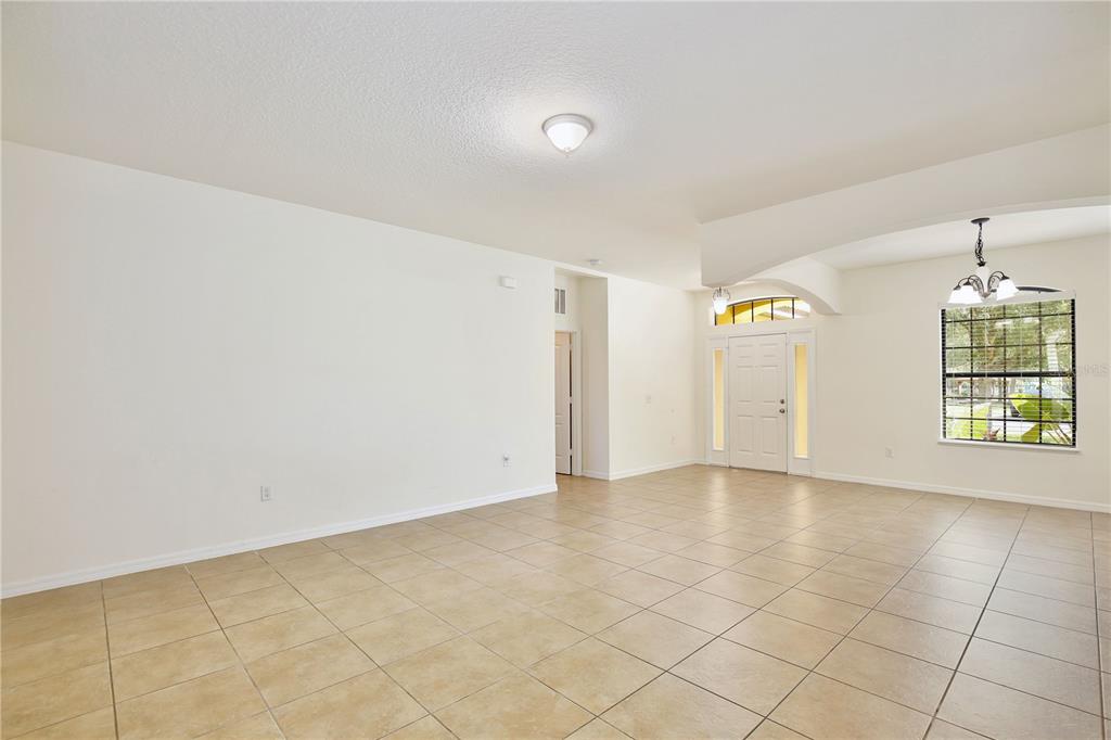 An empty room with beige tile flooring, white walls, and a front entryway — 3908 COASTAL BREEZE DRIVE, KISSIMMEE, FL