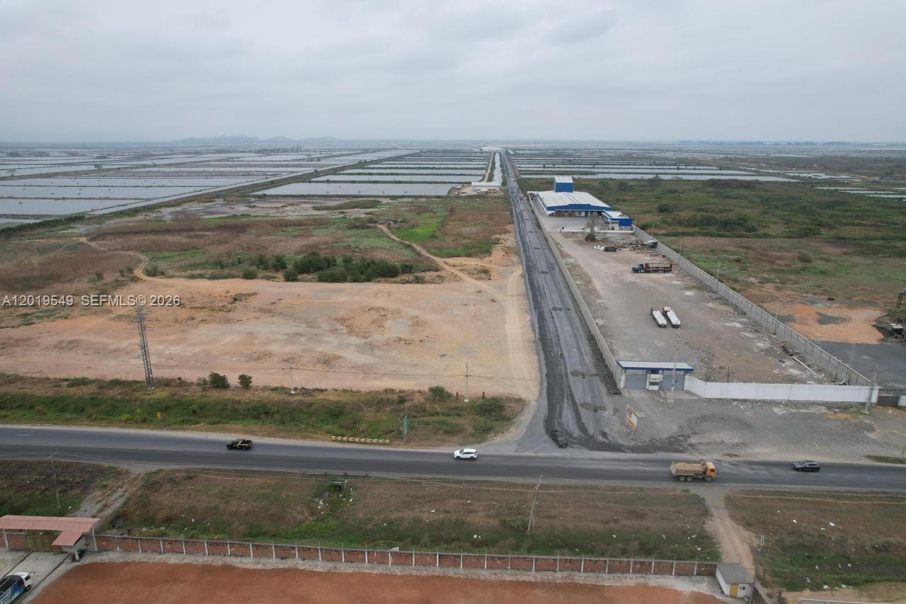An aerial view shows a paved road intersecting a highway near a large industrial facility — KM 10 VIA DURAN-TAMBO, EC, EC