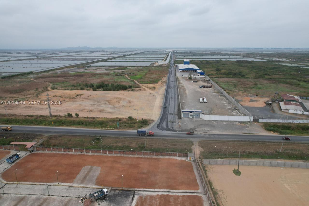 An aerial view shows a paved road intersecting a highway near industrial buildings and ponds — KM 10 VIA DURAN-TAMBO, EC, EC