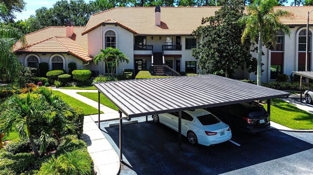 An aerial view shows a multi-story building with a tiled roof and a covered parking area — 2632 ENTERPRISE ROAD E UNIT A12, CLEARWATER, FL