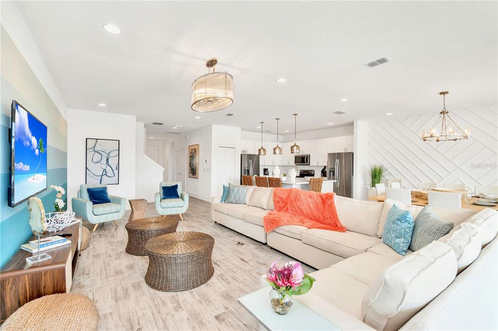 An open-concept living room and kitchen feature a large sectional sofa and light tile flooring — 537 MARCELLO BOULEVARD, KISSIMMEE, FL