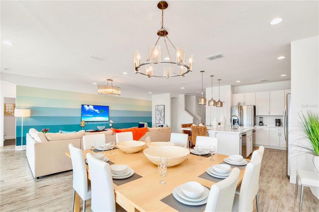 A dining area with a light wood table sits in front of an open-concept kitchen — 537 MARCELLO BOULEVARD, KISSIMMEE, FL