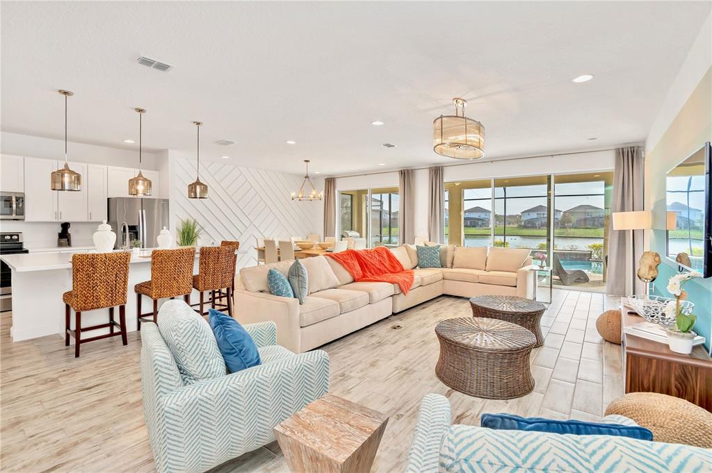 An open-concept living room and kitchen featuring light wood-look tile floors and a lake view — 537 MARCELLO BOULEVARD, KISSIMMEE, FL
