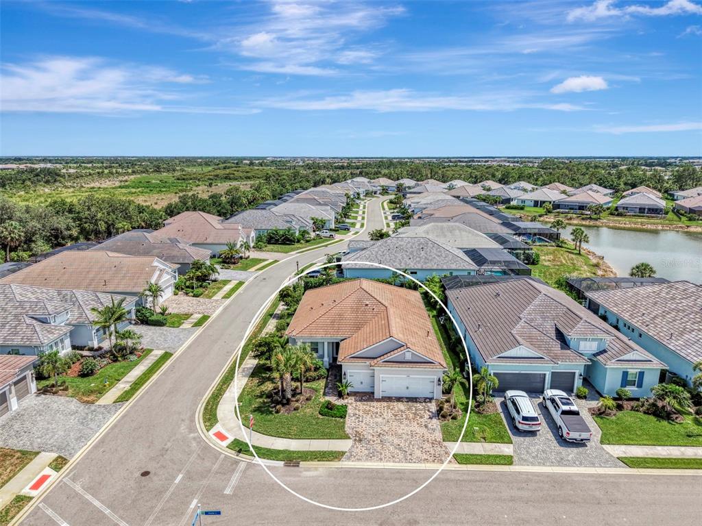 An aerial view shows a single-story house with a tiled roof and a paved driveway — 12365 VIESTE COURT, VENICE, FL