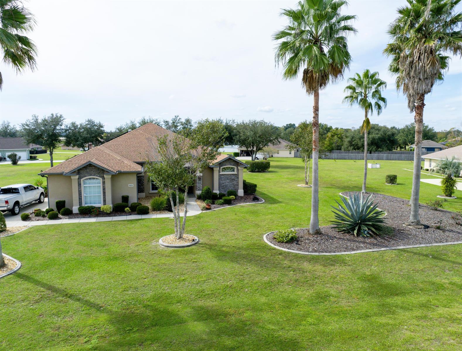 An aerial view shows a single-story house with a large lawn and palm trees — 9908 SE 67th Avenue Road, FL 34420, FL