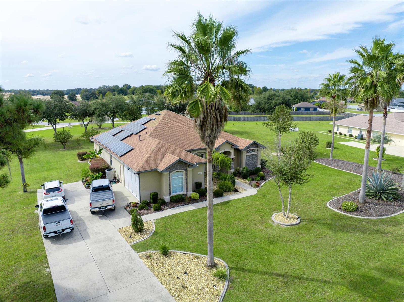 An aerial view shows a single-story house with solar panels, a driveway, and palm trees — 9908 SE 67th Avenue Road, FL 34420, FL