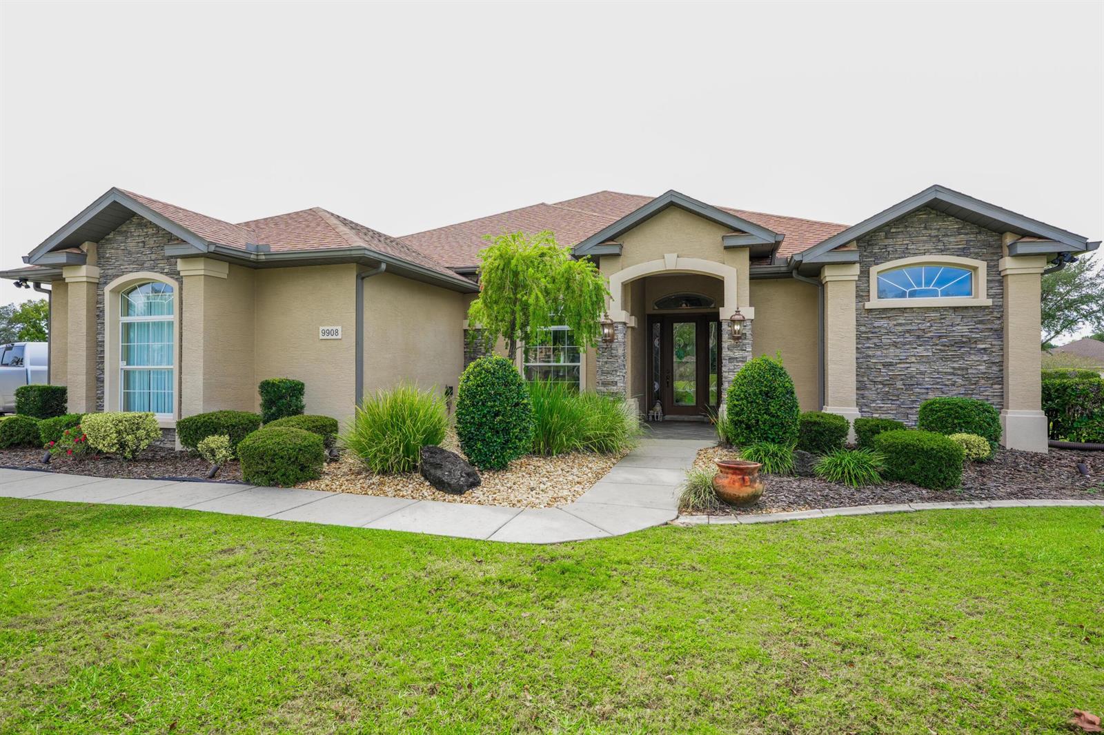 A single-story house features a stone facade, tan stucco walls, and a landscaped front yard — 9908 SE 67th Avenue Road, FL 34420, FL