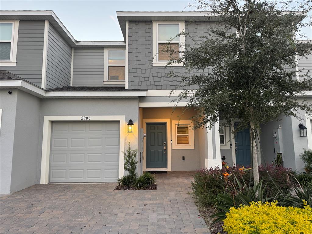 A two-story townhouse exterior features a gray garage, a blue front door, and stone pavers — 2906 CANARY AVENUE, DAVENPORT, FL