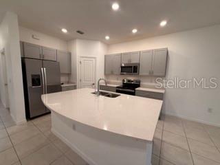 A kitchen with gray cabinets, stainless steel appliances, and a large white island countertop — 2906 CANARY AVENUE, DAVENPORT, FL