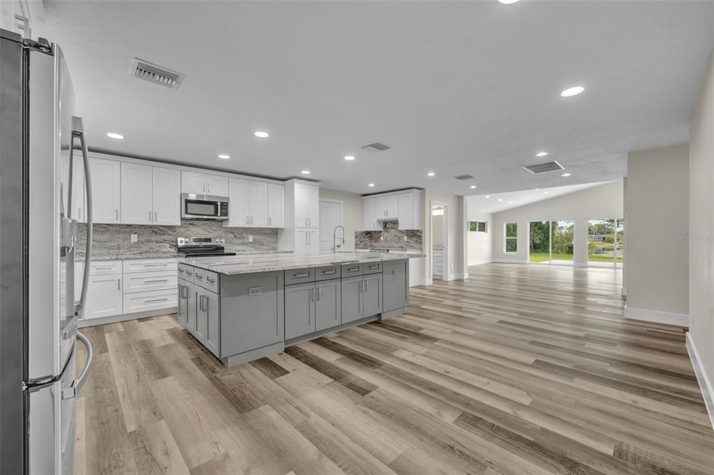 A kitchen with white cabinets, a gray island, and wood-look flooring in an open-concept space — 5762 SHERYL ANITA STREET, OVIEDO, FL