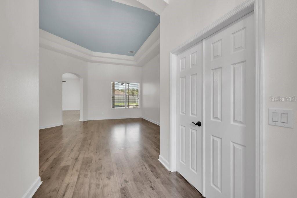 A view from a hallway into a room with a tray ceiling and wood flooring — 11109 WEMBLEY LANDING DRIVE, LITHIA, FL