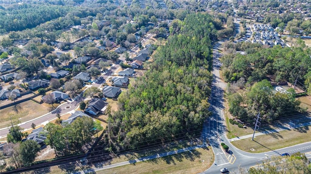 An aerial view shows a wooded lot situated between a residential neighborhood and a road — 8717 SW ARCHER ROAD, GAINESVILLE, FL