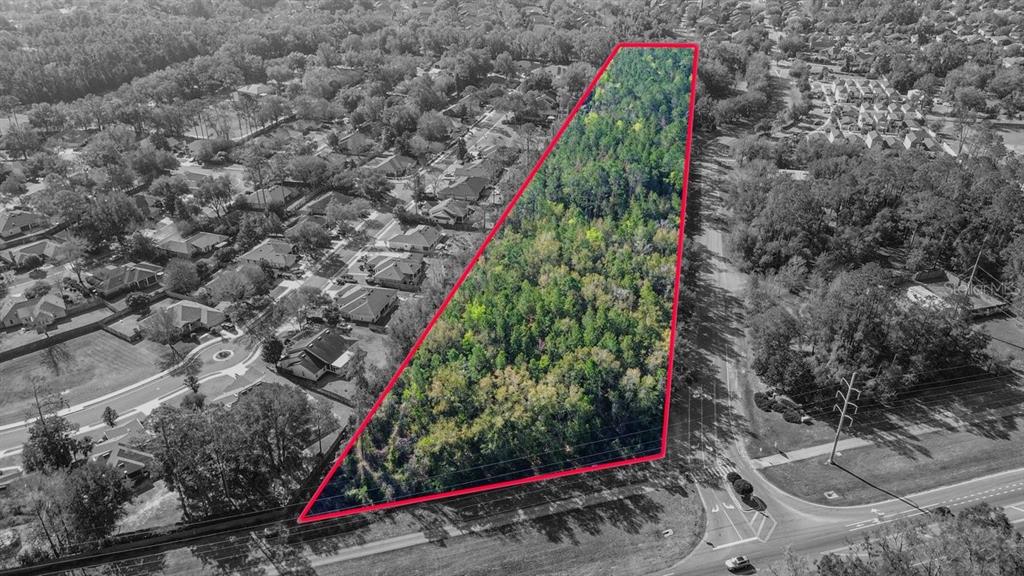An aerial view shows a triangular, wooded plot of land outlined in red — 8717 SW ARCHER ROAD, GAINESVILLE, FL