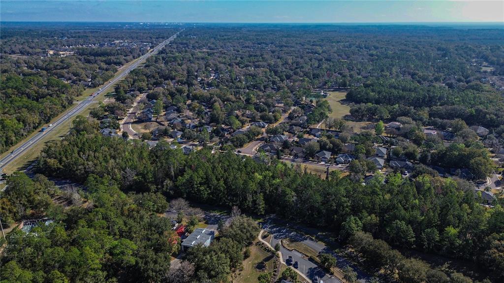 An aerial view shows a suburban neighborhood surrounded by dense forest and a nearby highway — 8717 SW ARCHER ROAD, GAINESVILLE, FL