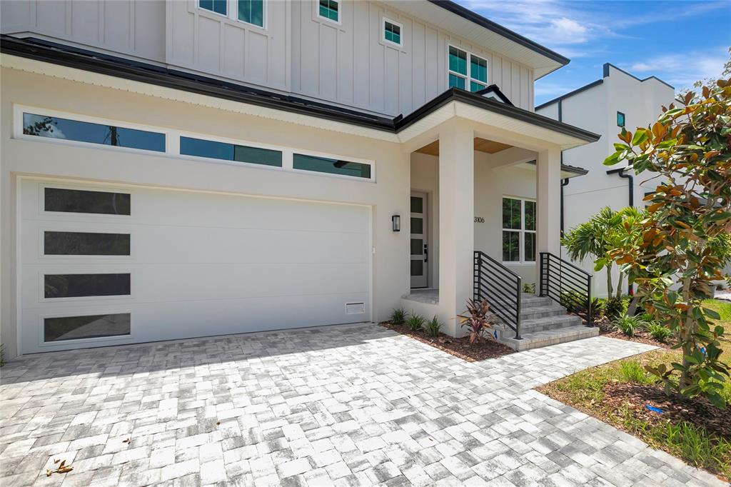 A modern two-story house features a white garage, a covered entryway, and a paved driveway — 3106 W COACHMAN AVENUE, TAMPA, FL