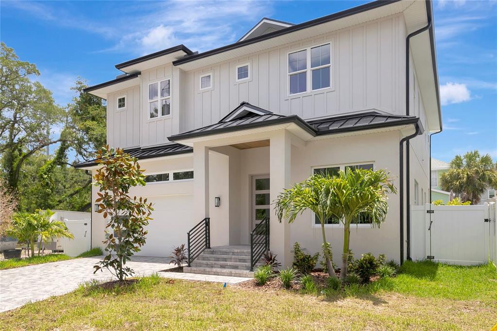 A two-story modern house with white vertical siding, a metal roof, and a paved driveway — 3106 W COACHMAN AVENUE, TAMPA, FL