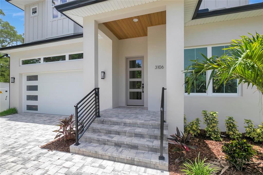 The exterior of a modern home features a paved driveway, stone steps, and a front door — 3106 W COACHMAN AVENUE, TAMPA, FL