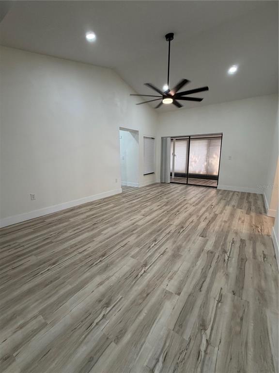 An empty room features light wood-look flooring, white walls, a ceiling fan, and sliding glass doors — 339 PEMBROKE LANE S UNIT 228, VENICE, FL
