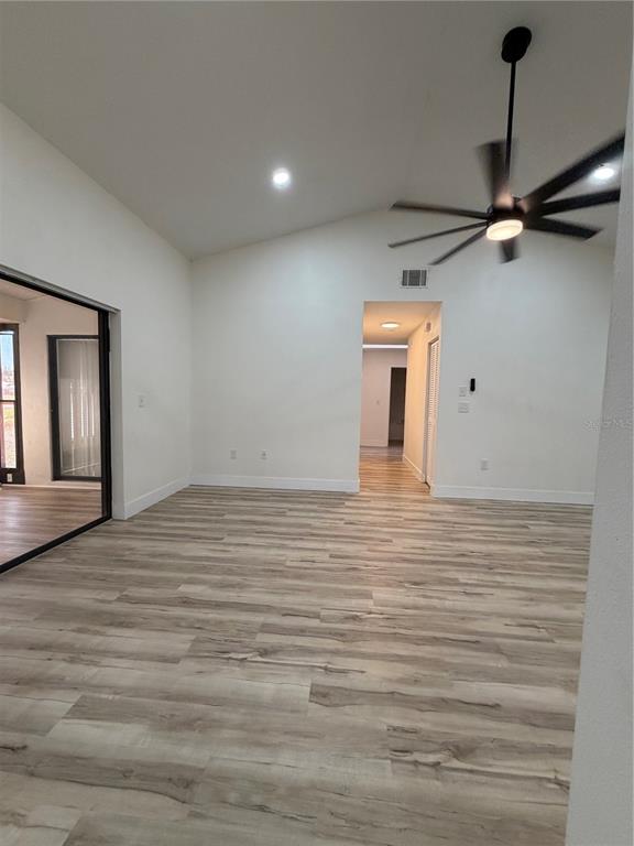 A bright, open living room features light wood-look flooring, a vaulted ceiling, and a ceiling fan — 339 PEMBROKE LANE S UNIT 228, VENICE, FL