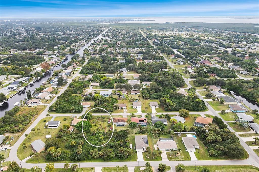 An aerial view shows a vacant, wooded lot circled in a residential neighborhood near canals — 4477 HARRINGTON STREET, PORT CHARLOTTE, FL