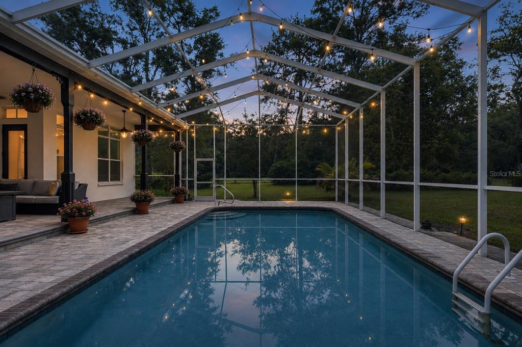 A covered front porch features dark wood flooring, two rocking chairs, and potted flowers — 17163 BENES ROUSH ROAD, BROOKSVILLE, FL