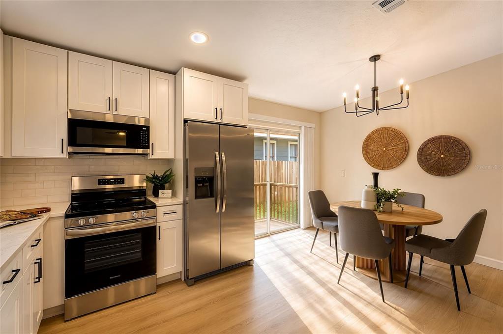 A kitchen and dining area with white cabinets, stainless steel appliances, and a wooden table — 1316 E GIDDENS AVENUE, TAMPA, FL