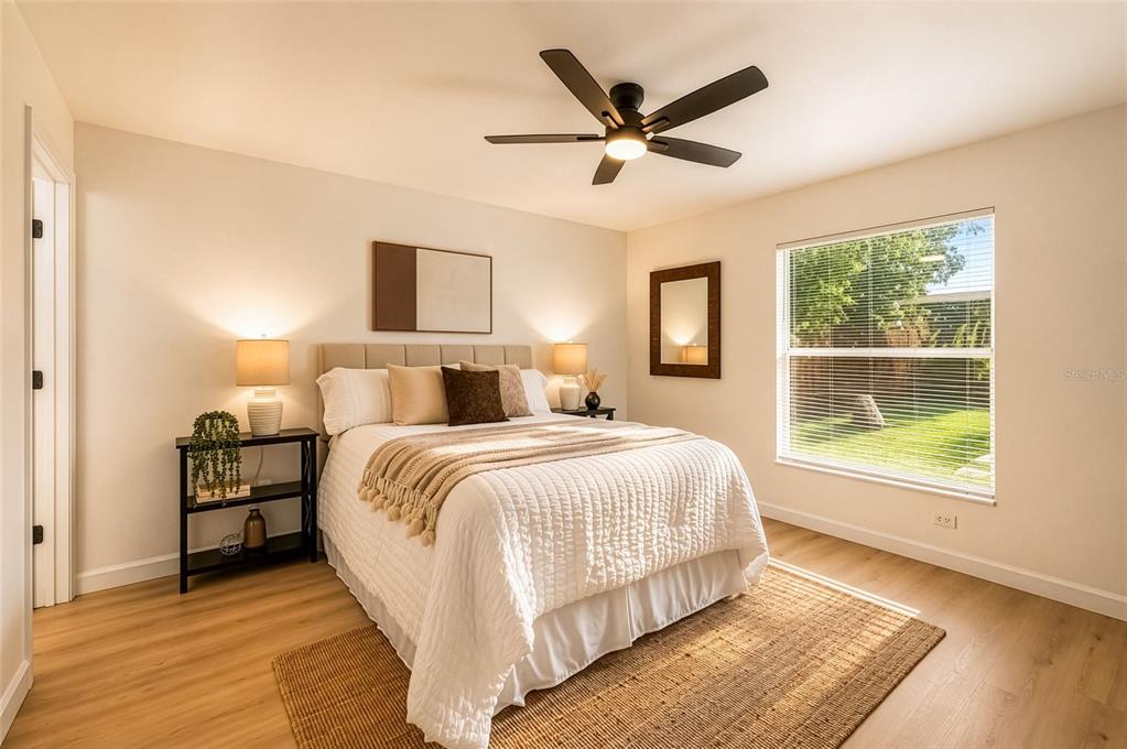 A bedroom features a queen bed, a ceiling fan, light wood flooring, and a window — 1316 E GIDDENS AVENUE, TAMPA, FL